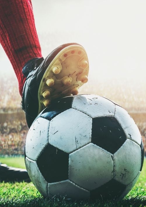 A soccer cleat rests on a ball on a field with a stadium background, representing the FIFA World Cup.