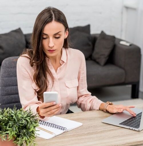 An uncommitted remote worker at her desk split between her laptop and phone, illustrating a workplace situationship.