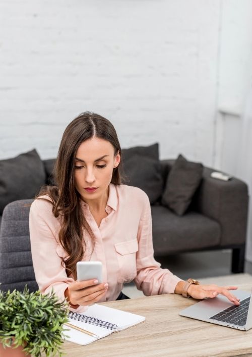 An uncommitted remote worker at her desk split between her laptop and phone, illustrating a workplace situationship.