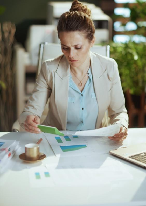 A focused Gen X worker in an office uses a calculator and financial charts at a desk to review retirement plans.
